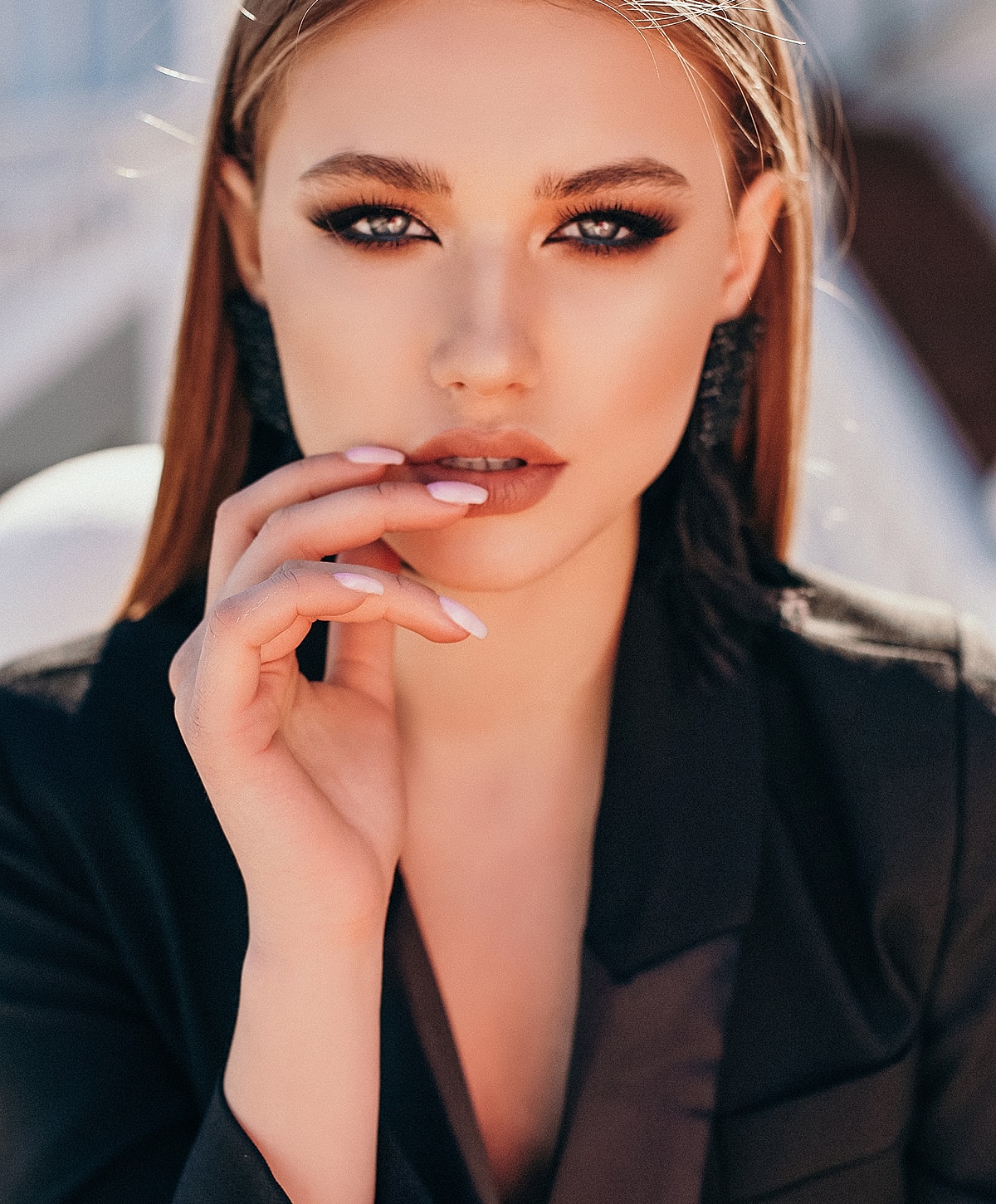 Woman in black blazer, striking pose with hand.