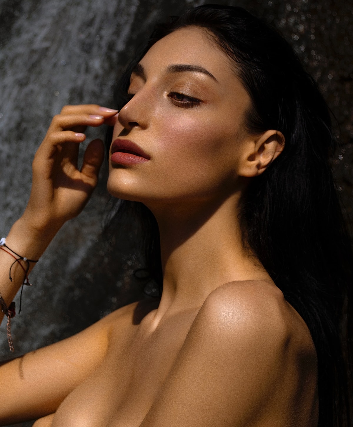 Model posing near a waterfall in natural light.